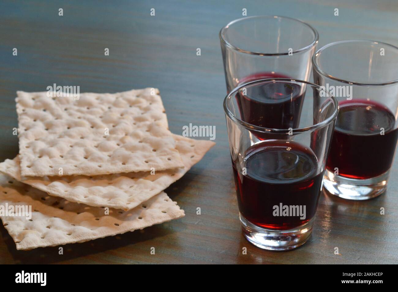 La cena del Signore con pane azzimo e tre piccole tazze di vino su tavola di legno ciano Foto Stock