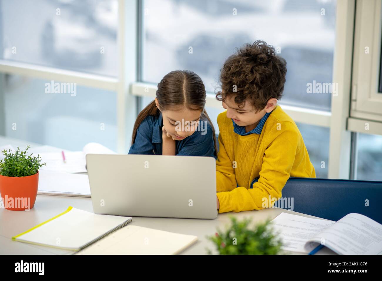 Ragazzo aiutando una ragazza in utilizzando il computer portatile Foto Stock