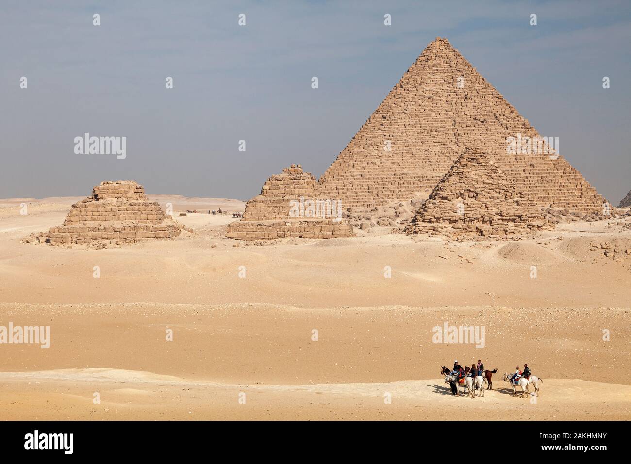 Persone corsa dei cavalli attraverso il deserto di sabbia su Giza altopiano presso le Grandi Piramidi d'Egitto Foto Stock