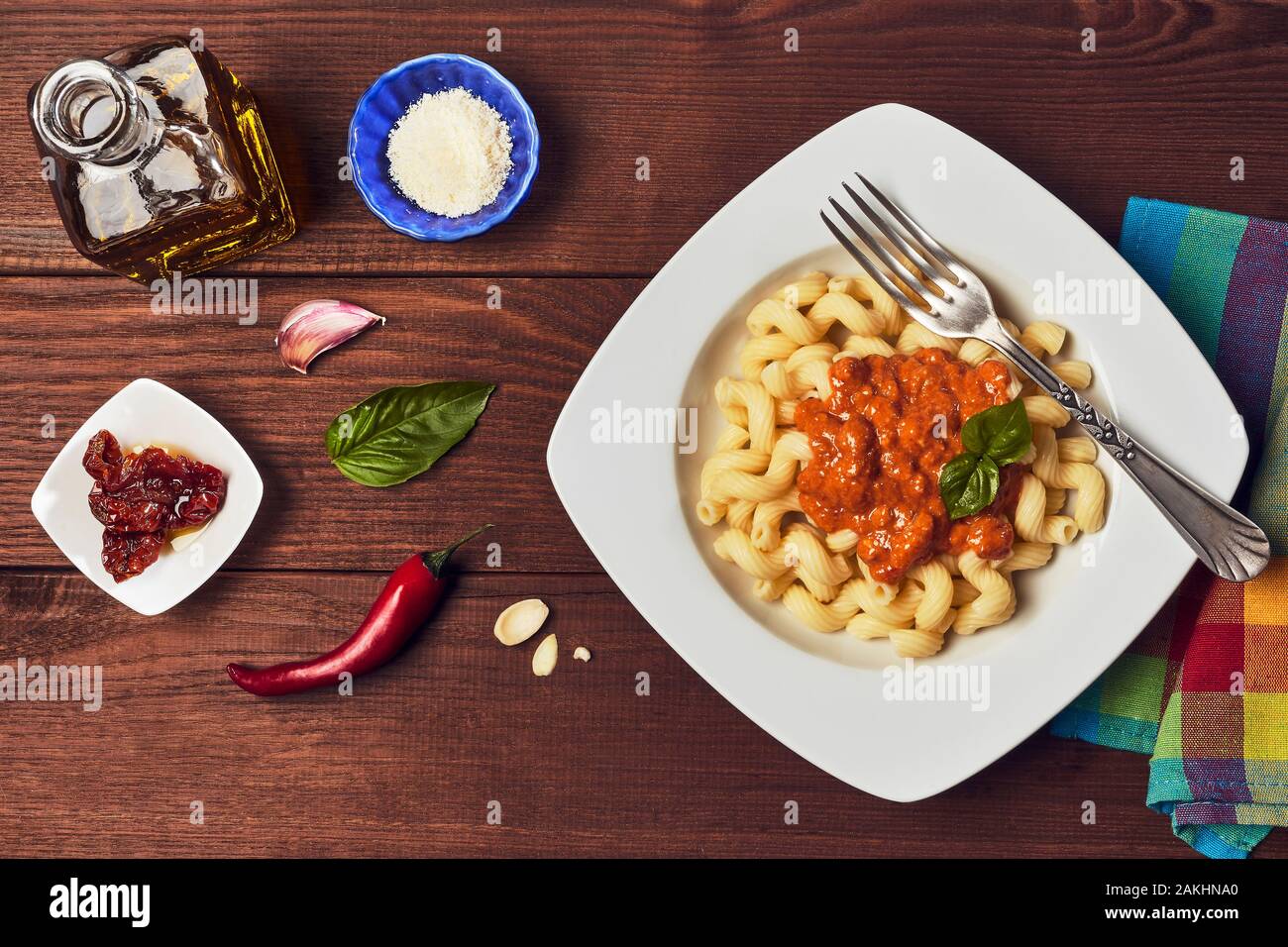 Pesto rosso pasta con gli ingredienti su di un legno scuro dello sfondo. Foto Stock