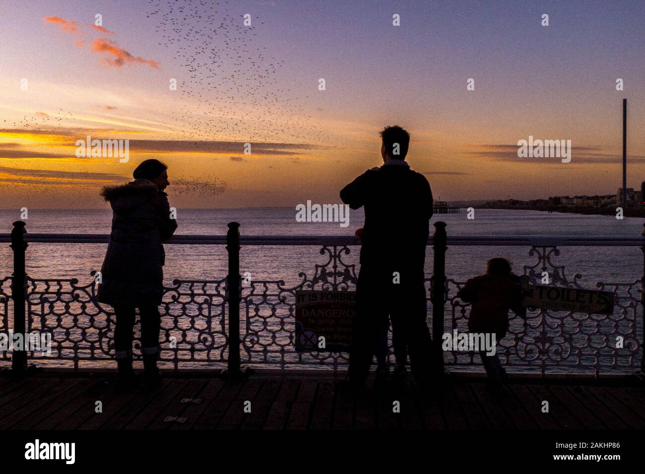 Starling Murmuration oltre il molo di Brighton al tramonto in inverno prima del riposo per la serata, Brighton, Regno Unito Foto Stock