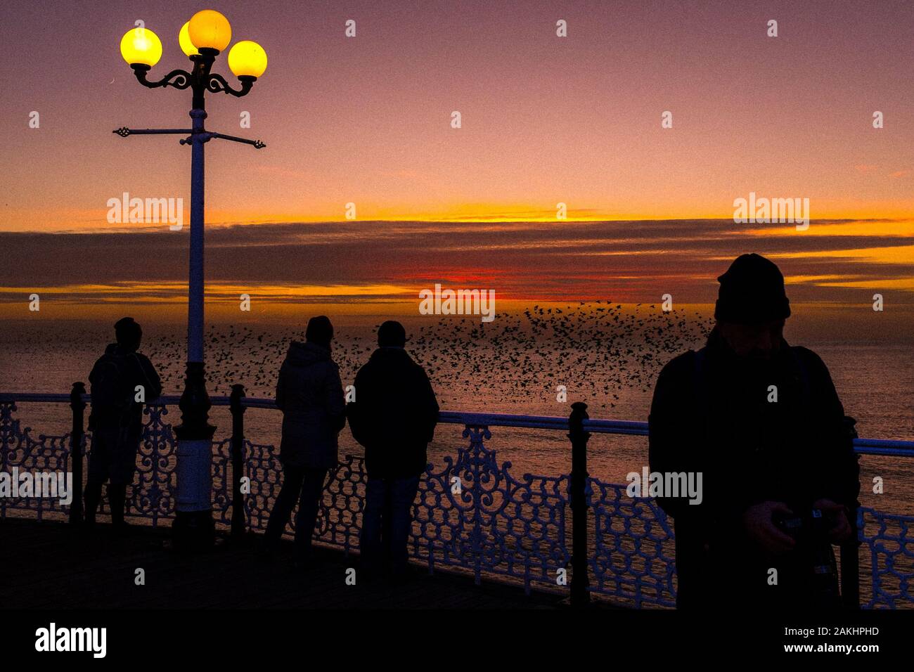 Starling Murmuration oltre il molo di Brighton al tramonto in inverno prima del riposo per la serata, Brighton, Regno Unito Foto Stock