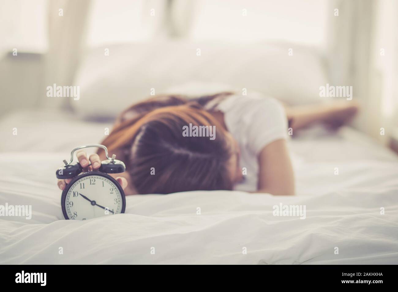 Bella asiatica giovane donna disattivare la sveglia di buon mattino per dormire con closeup primo piano sveglia, rilassarsi e concetto di stile di vita. Foto Stock