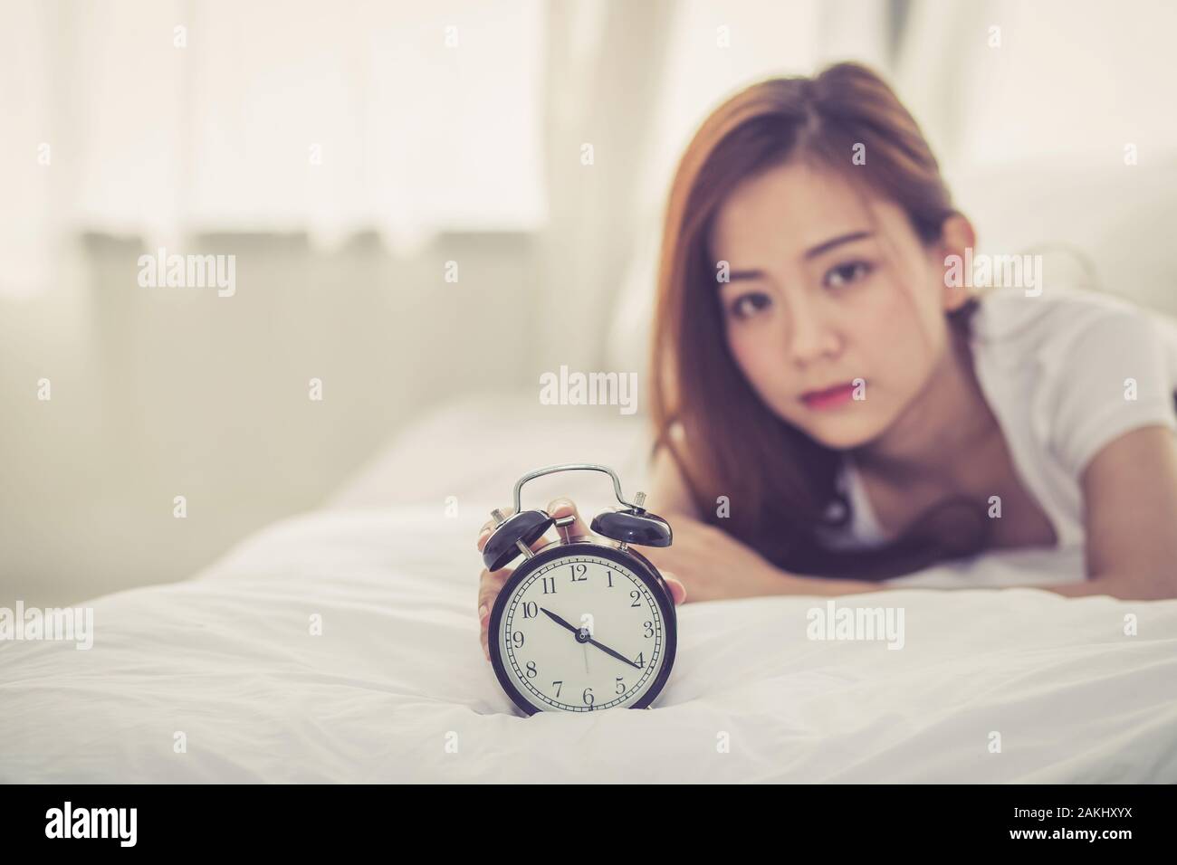 Bella asiatica giovane donna disattivare la sveglia di buon mattino per dormire con closeup primo piano sveglia, rilassarsi e concetto di stile di vita. Foto Stock