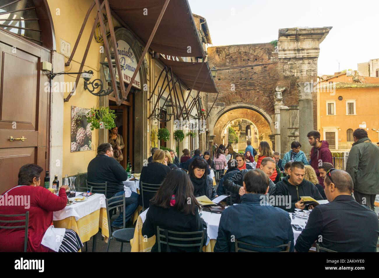 La gente sta mangiando all'aperto in una trattoria tipica in Ghetto, quartiere ebraico di Roma, con Portico di Octavia (Portico di Ottavia) sullo sfondo Foto Stock