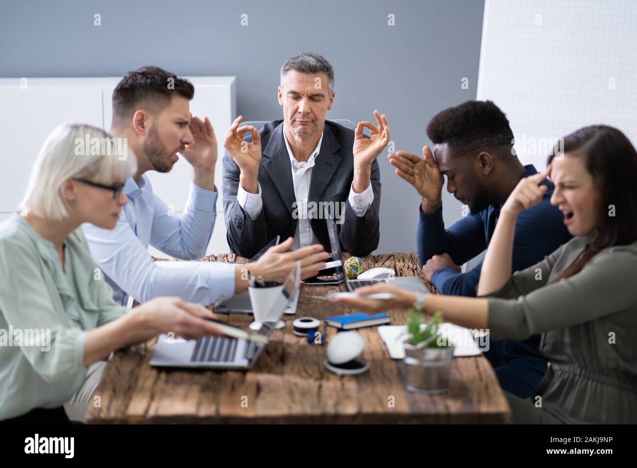 Imprenditore meditando mentre i suoi colleghi una conversazione in Office Foto Stock