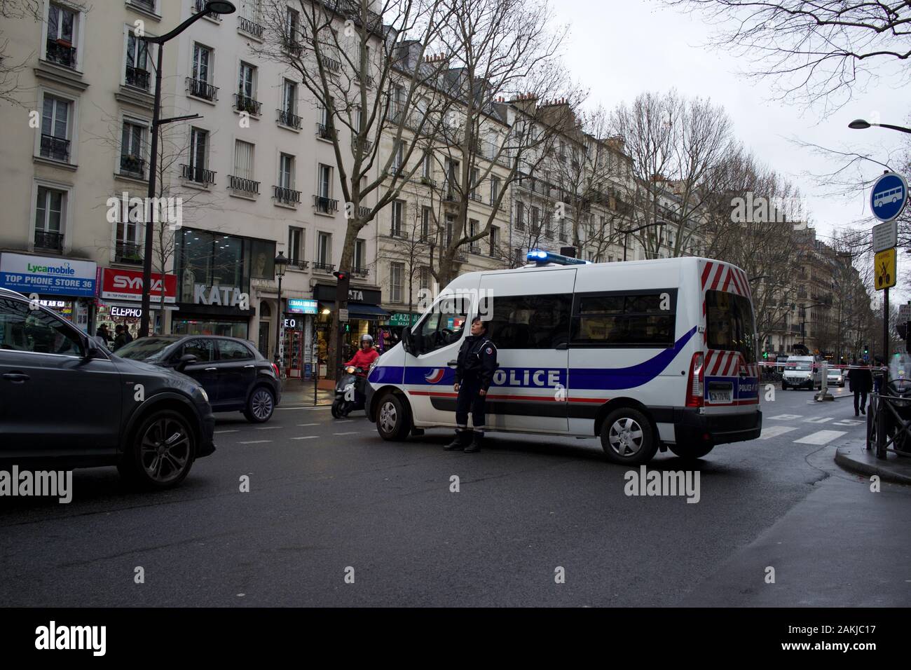 Furgone della polizia francese parcheggiato in strada, chiudendo la strada al traffico, come ufficiale di polizia sta vicino, in previsione delle proteste a causa delle riforme pensionistiche proposte dal governo, causando interruzioni di viaggio, sciopero di Parigi (la grève), boulevard Barbès, 75018, Parigi, Francia, 9th gennaio 2020 Foto Stock