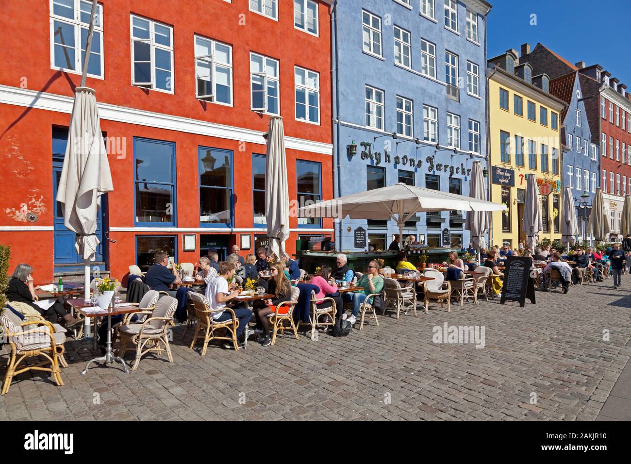 Gli storici ristoranti sul lungomare di Nyhavn, Copenhagen, attraggono centinaia di turisti e Copenaghen per un pranzo all'aperto in una soleggiata giornata primaverile. Foto Stock