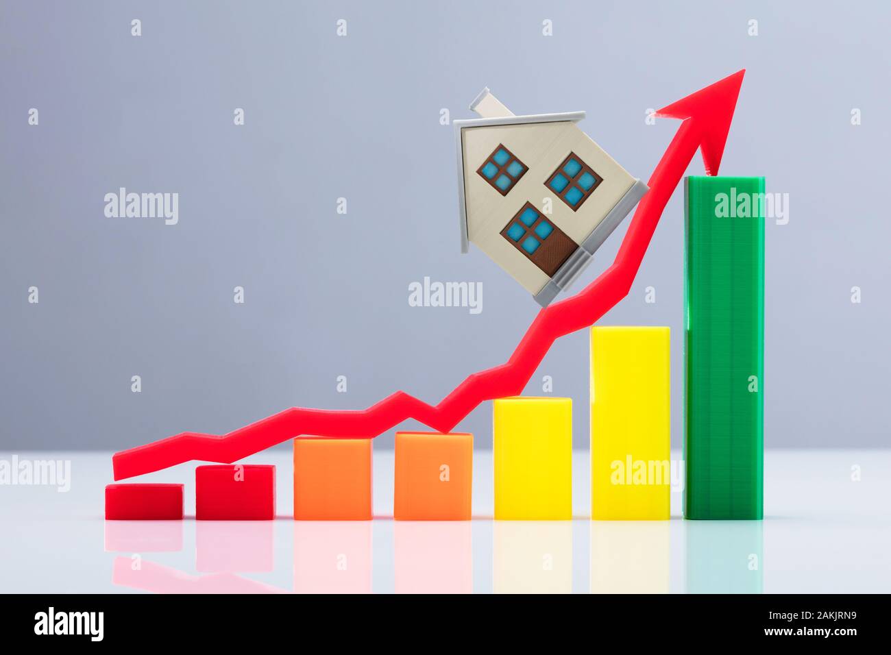 Un aumento del Business grafico e Freccia Rossa segno con casa modello sulla scrivania riflettente Foto Stock