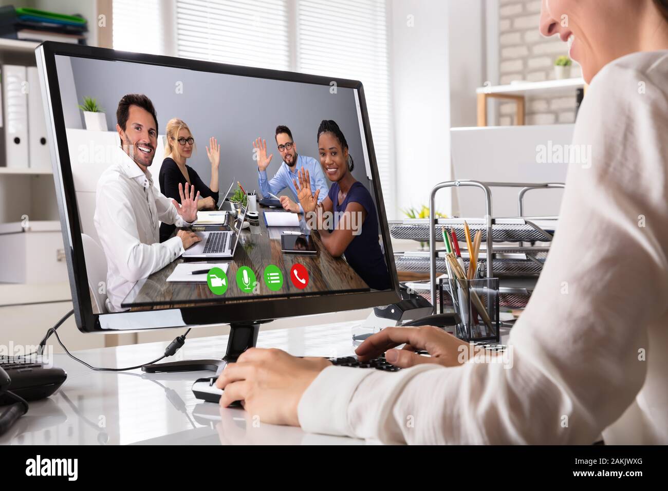 Giovane donna d'affari in videoconferenza con i colleghi saluto Lei sul computer portatile in ufficio Foto Stock