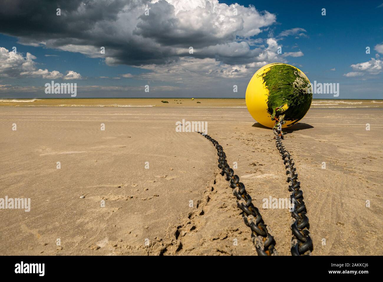 Bassa angolazione di una boa giallo coperto con alghe legata alla spiaggia di attesa per la prossima alta marea Foto Stock