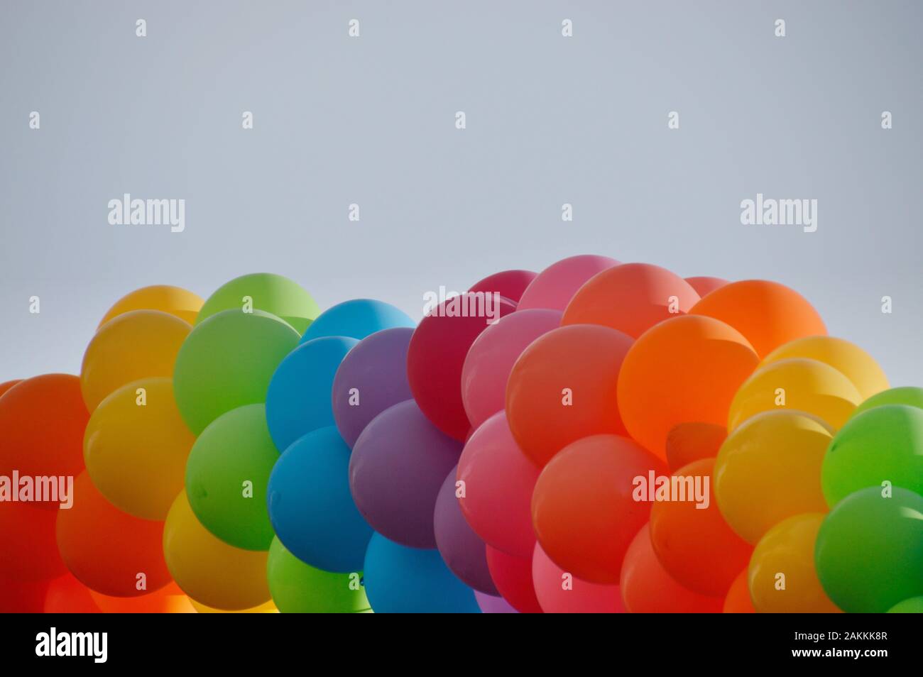 Un grappolo di palloncini colorati nella parte anteriore del cielo blu senza nuvole Foto Stock