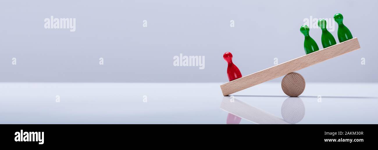 Close-up di colore rosso e verde pegni figure in equilibrio su altalena in legno Foto Stock