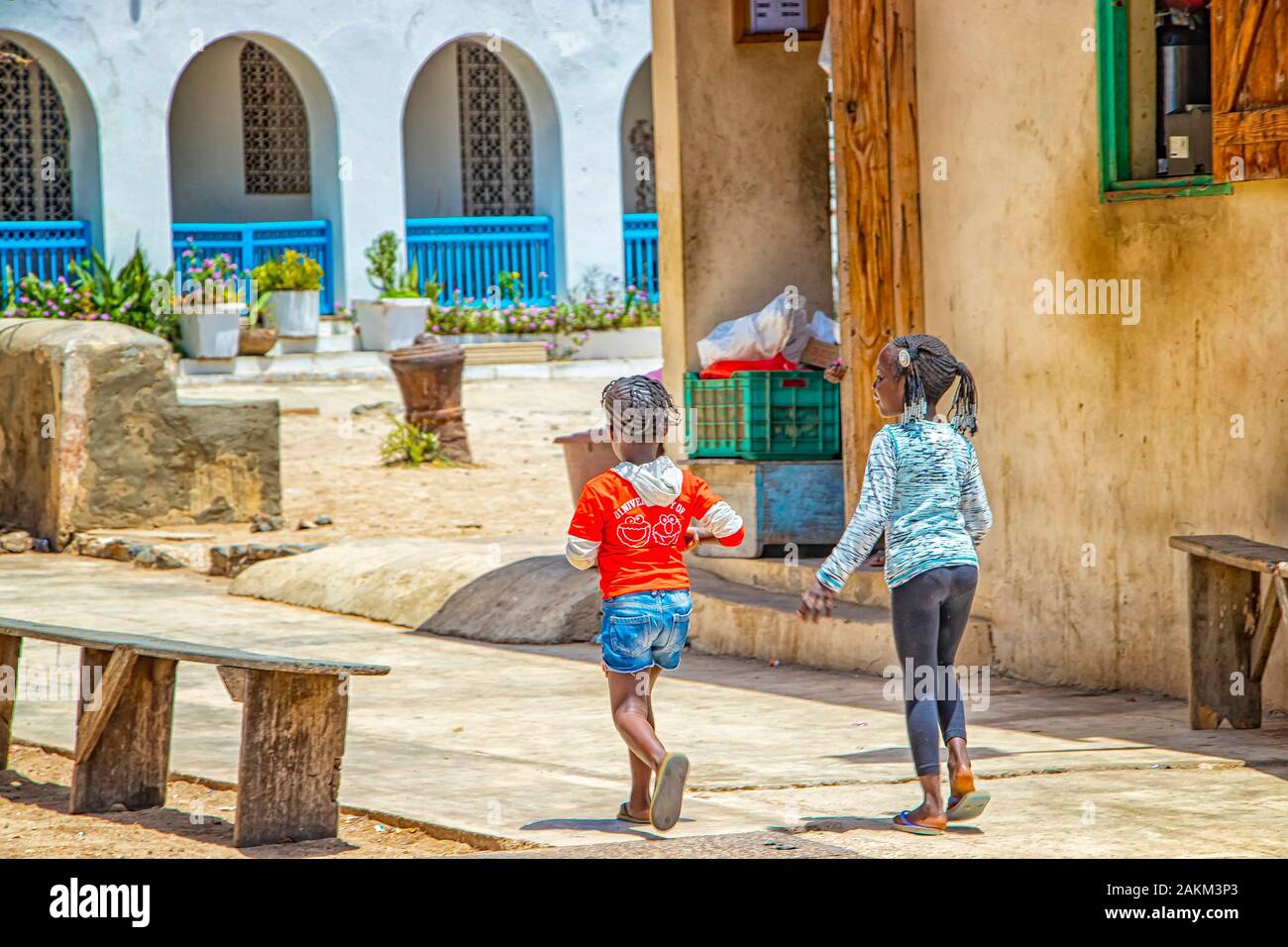 Isola di Goree, Senegal- 22 aprile 2019: ragazze non identificato a piedi lungo una strada di sabbia in una piccola città. Foto Stock