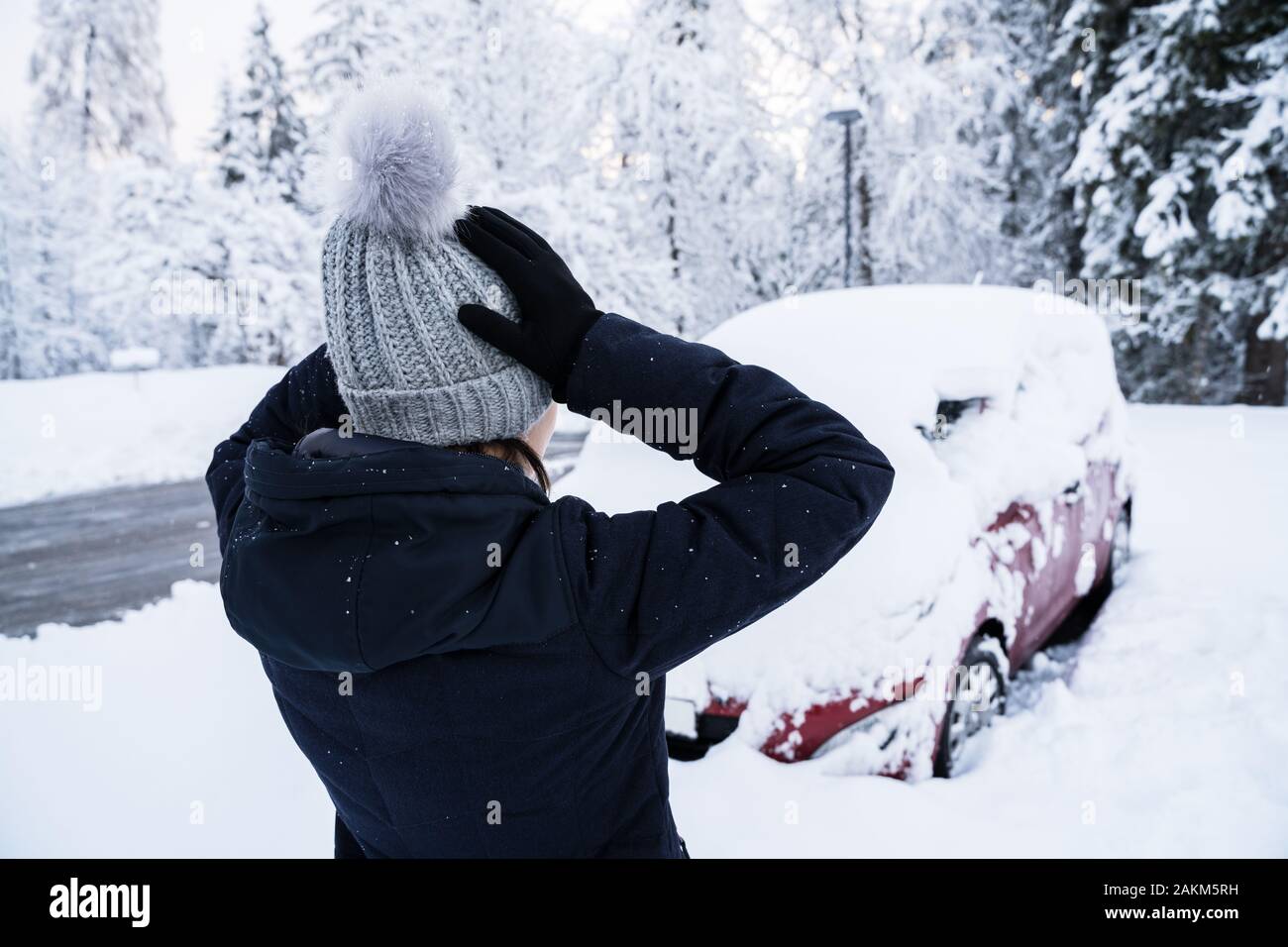 Scioccato Donna che guarda la macchina coperto con neve dopo la nevicata Foto Stock
