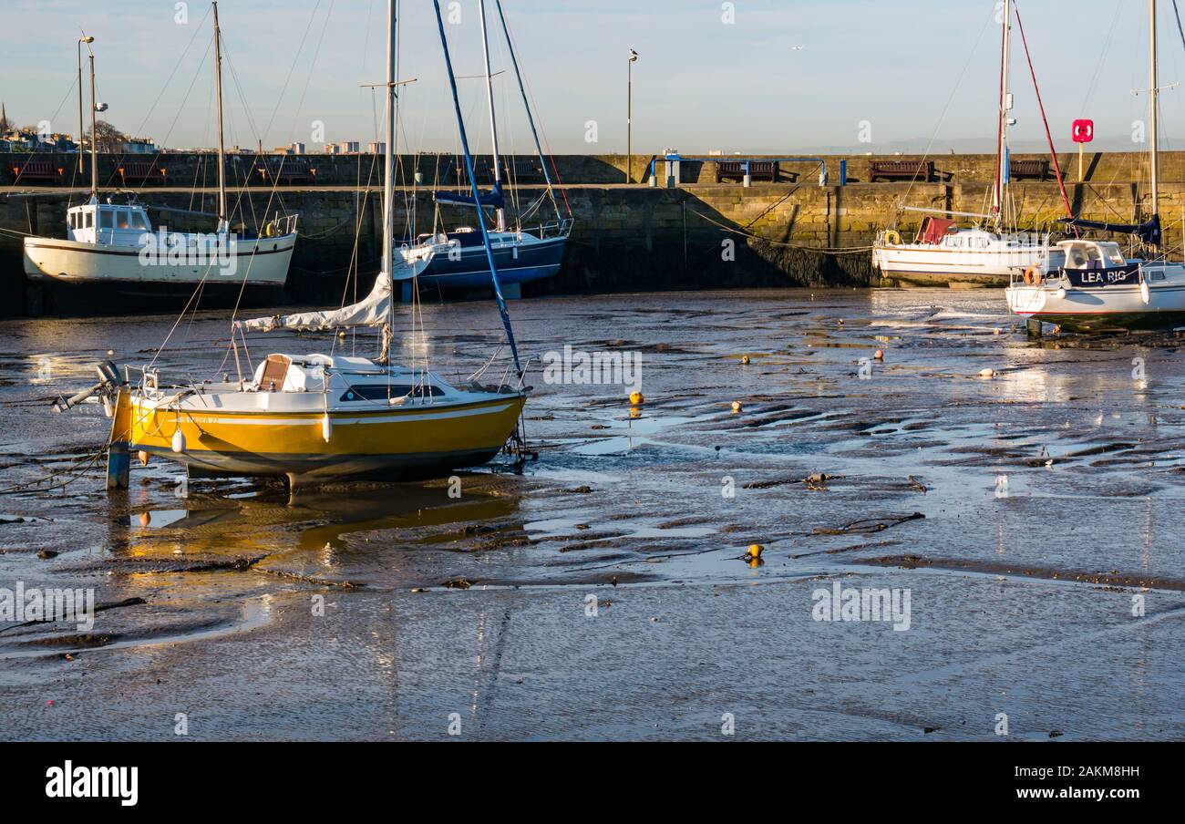 Barche a vela a terra nel fango con bassa marea, Fisherrow Harbour, Musselburgh, Scozia, Regno Unito Foto Stock