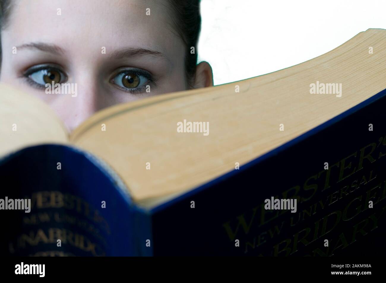 Femmina giovane studente di college di lettura di un grande libro di testo Foto Stock