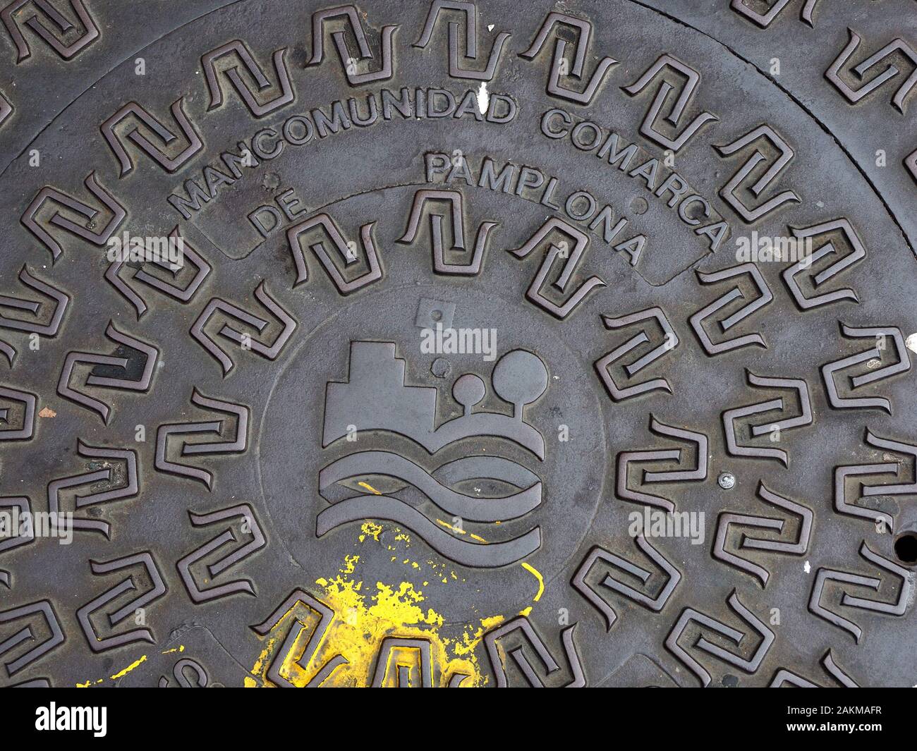 Splash di usura della vernice gialla di ossidare un nero lucido metallo colato drain-coprire goffrato con il simbolo e il titolo di città di Pamplona, nel nord della Spagna Foto Stock