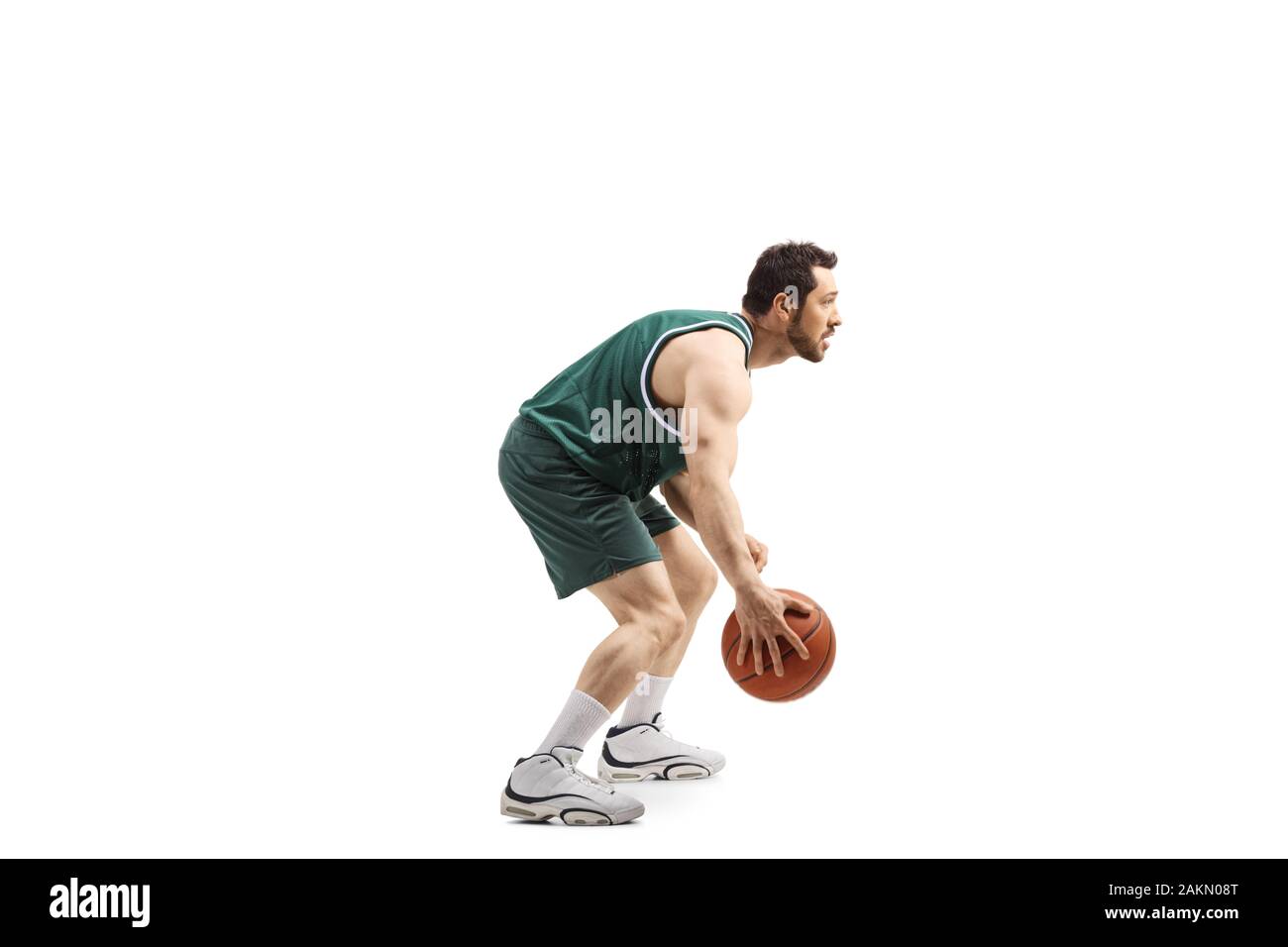 Lunghezza piena ripresa del profilo di un giocatore di pallacanestro in una maglia verde con una sfera isolata su sfondo bianco Foto Stock