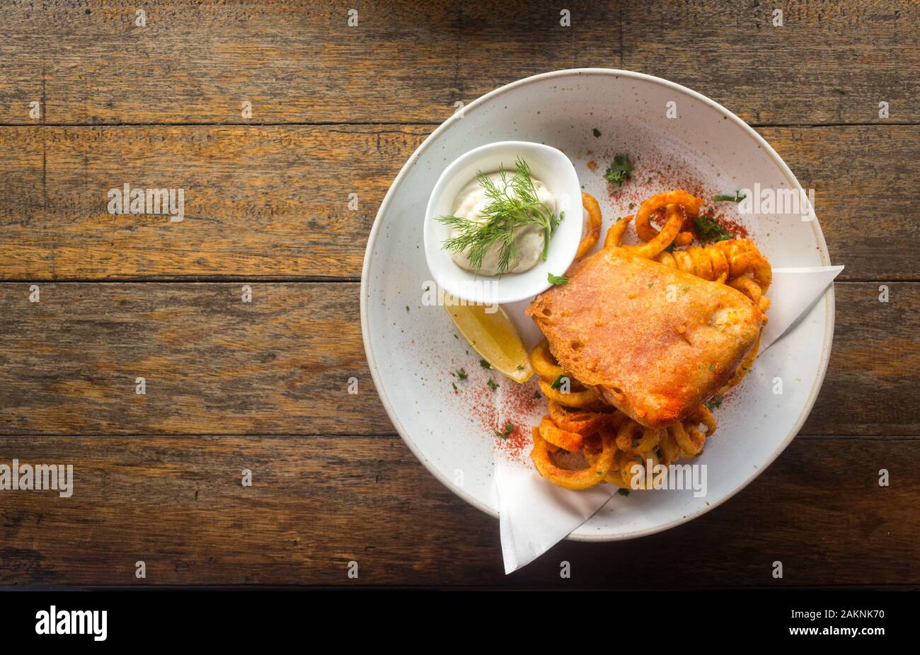 Pesce e patatine con salsa tartara in una piastra su un tavolo di legno dello sfondo. Foto Stock