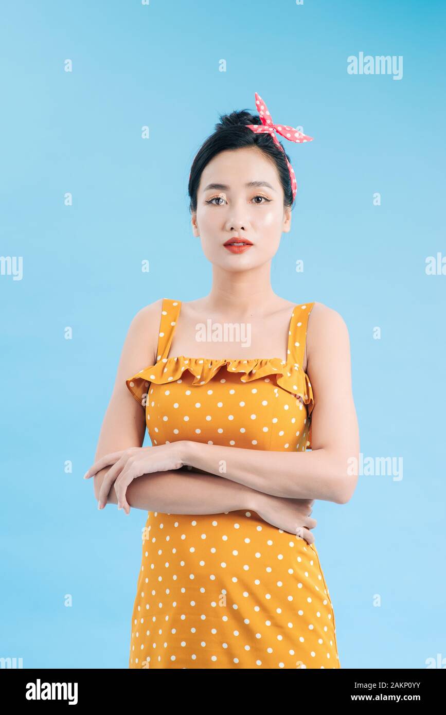 Grazioso alla moda giovane donna in posa su sfondo blu. Romantico adorabile ragazza di polka dot abito giallo Foto Stock