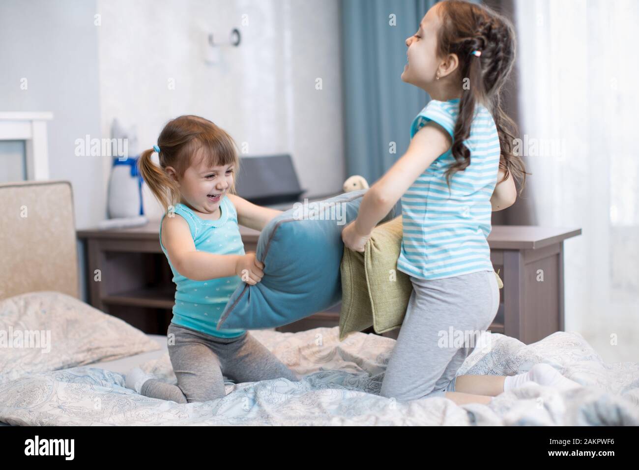 Bambini sorelle divertirsi giocando con cuscini in camera da letto a casa Foto Stock