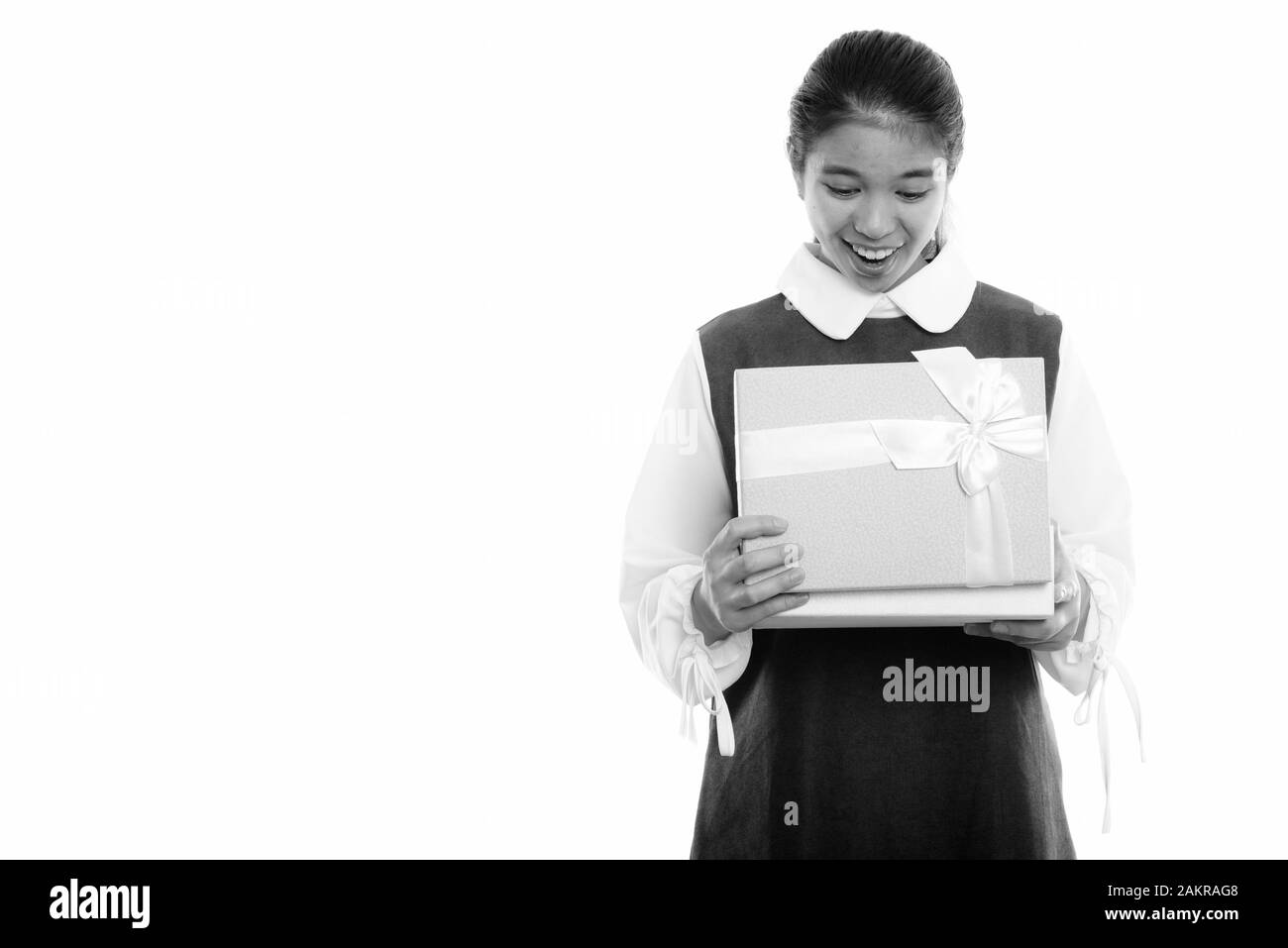 Studio scatto di giovane felice donna asiatica sorridente mentre apre scatola regalo Foto Stock