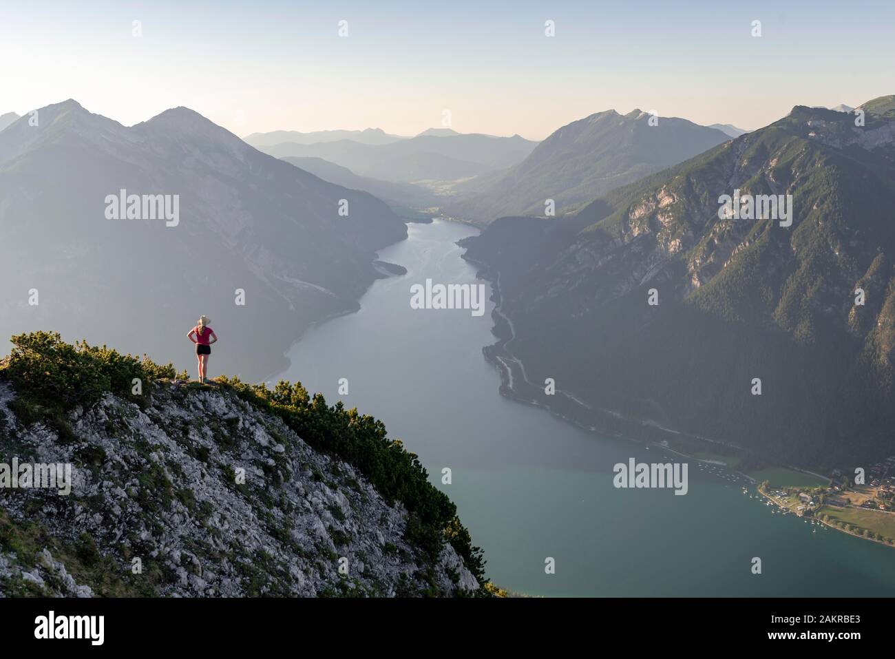Giovane donna che si affaccia su un paesaggio di montagna, vista dal monte Baerenkopf al Lago Achensee, sinistra e Seebergspitze Seekarspitze, destra Rofan Foto Stock