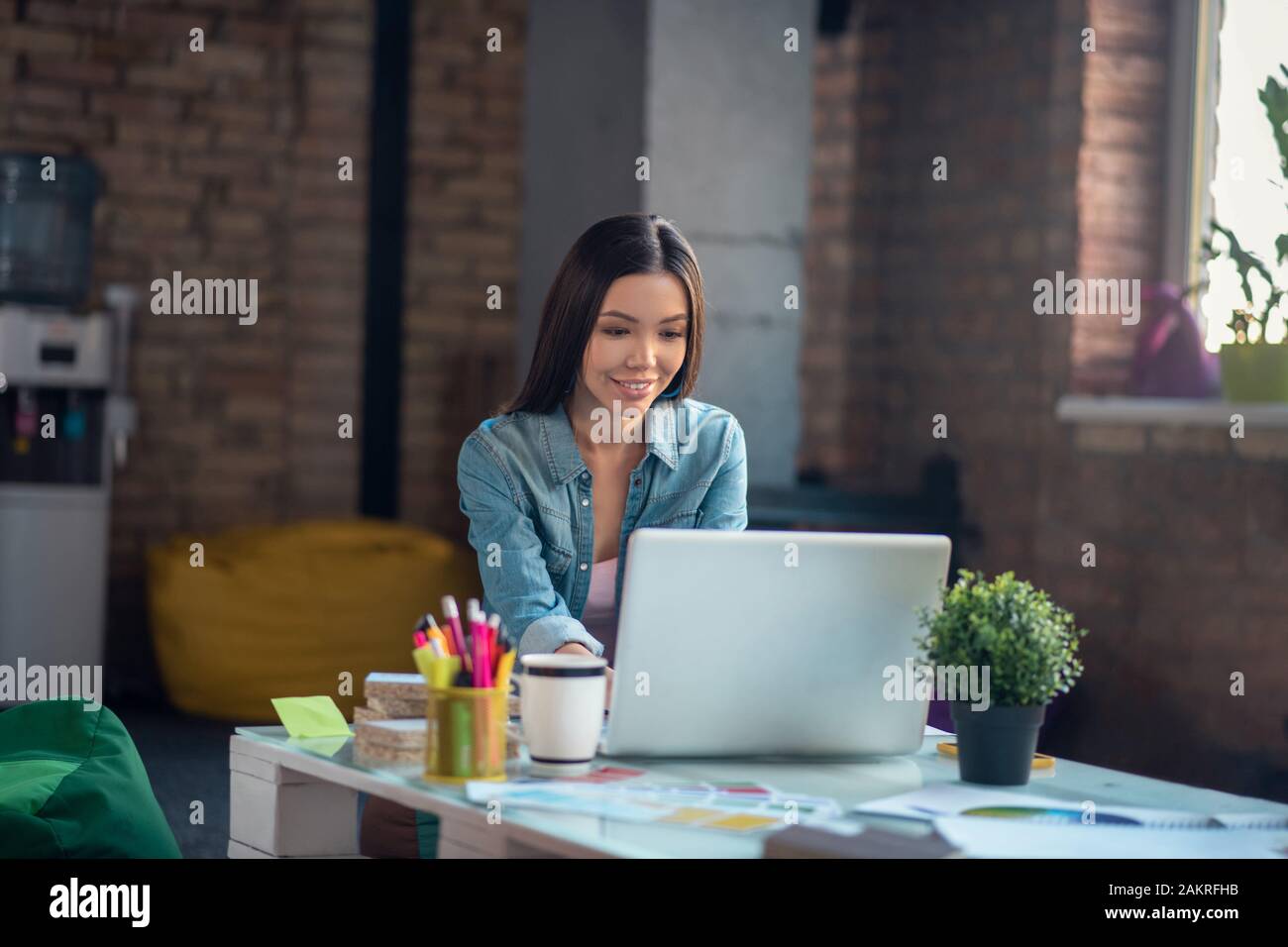 Gioiosa donna asiatica guardando lo schermo del laptop Foto Stock