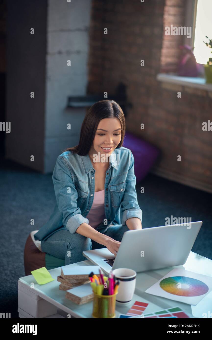 Positivo bella giovane donna digitando sulla tastiera Foto Stock