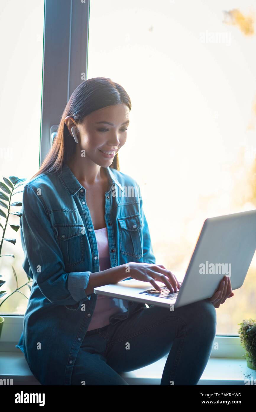Felice felice donna seduta in auricolari wireless Foto Stock