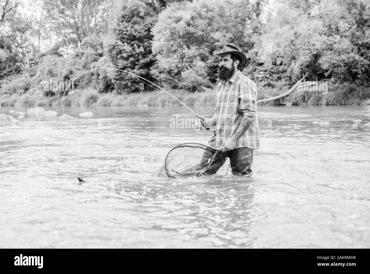 La pesca hobby. Barbuto brutale fisher la cattura di pesci trote con net. La pesca è un sorprendente accessibile ricreativo sport all'aperto. Se regolarmente del pesce Foto Stock