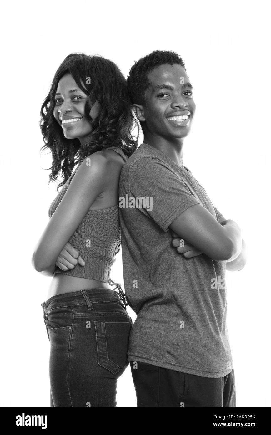 Studio shot di felice Africano nero sorella e fratello sorridente con le braccia incrociate e dorso a dorso Foto Stock