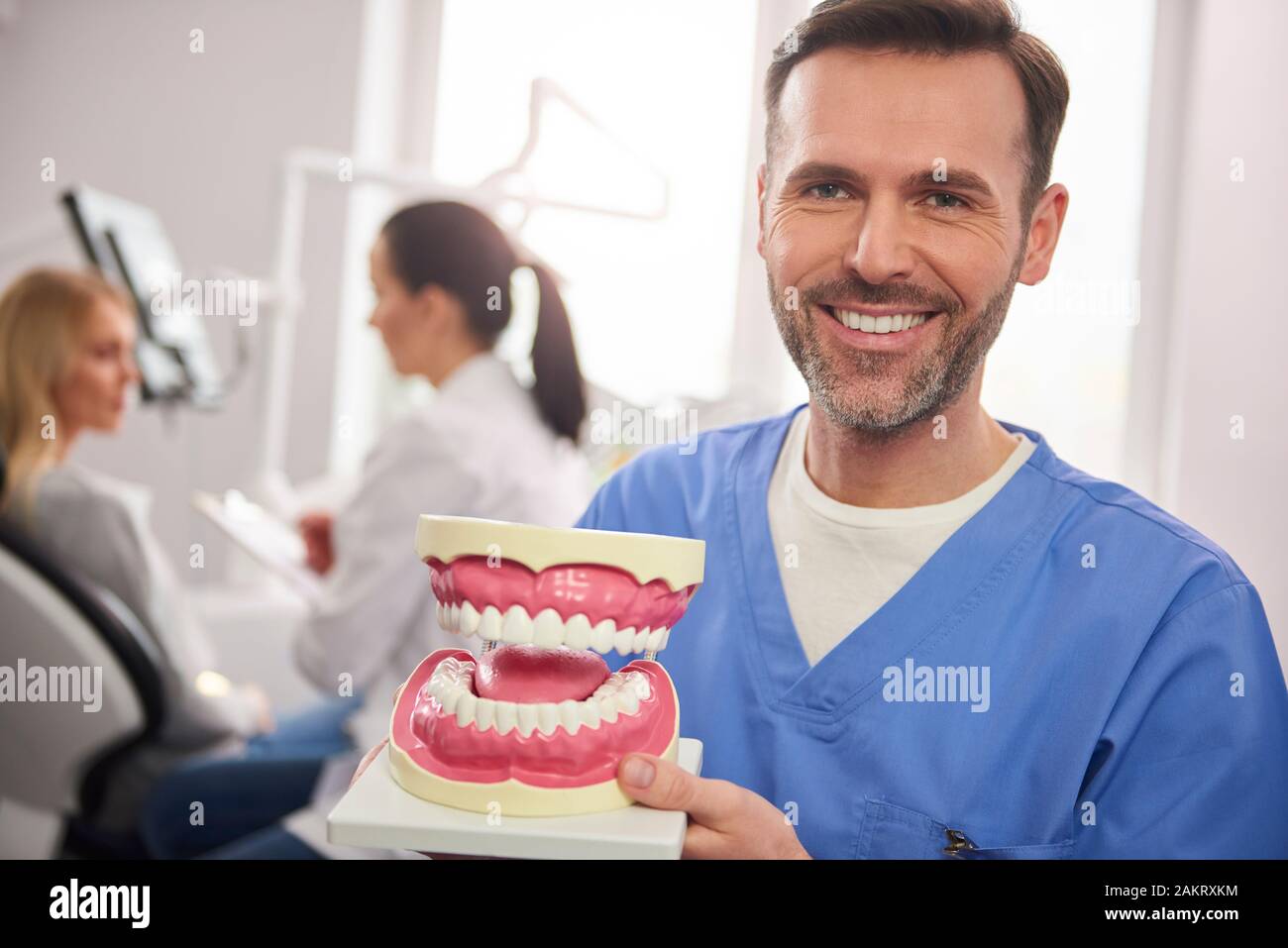 Sorridente dentista che mostra una protesi artificiale Foto Stock