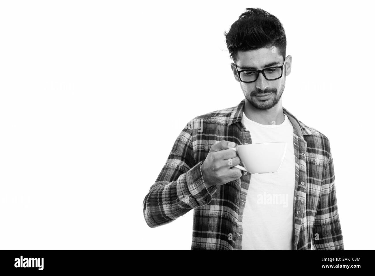 Studio shot del giovane uomo persiano holding e guardando a tazza da caffè Foto Stock