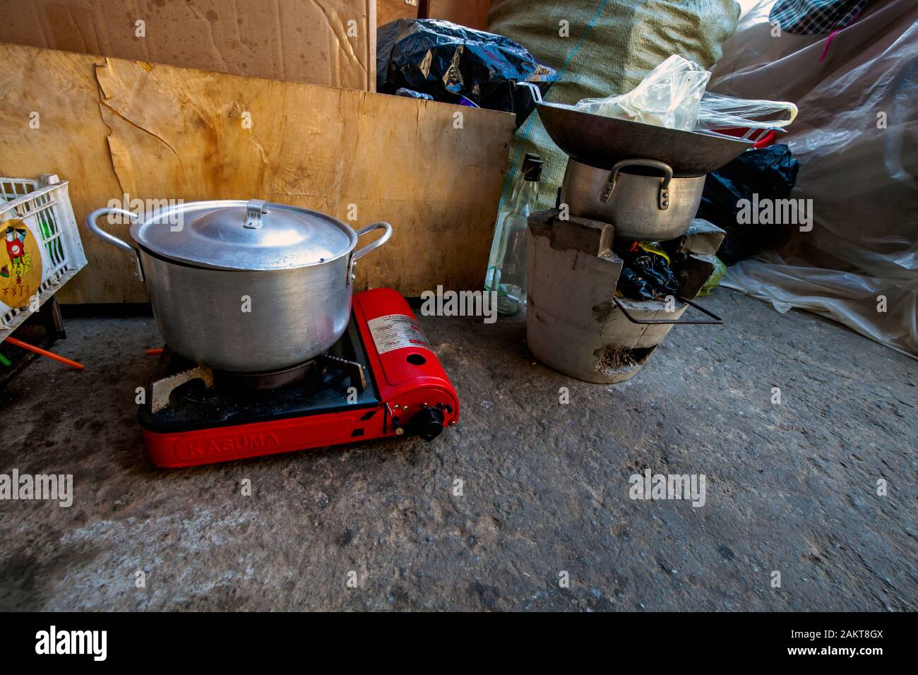 Un portatile a propano e stufa a legna per la stufa di cemento sono utilizzate nella cucina di fortuna di un povero senzatetto famiglia scavenger in Kampong Cham, Cambogia. Foto Stock