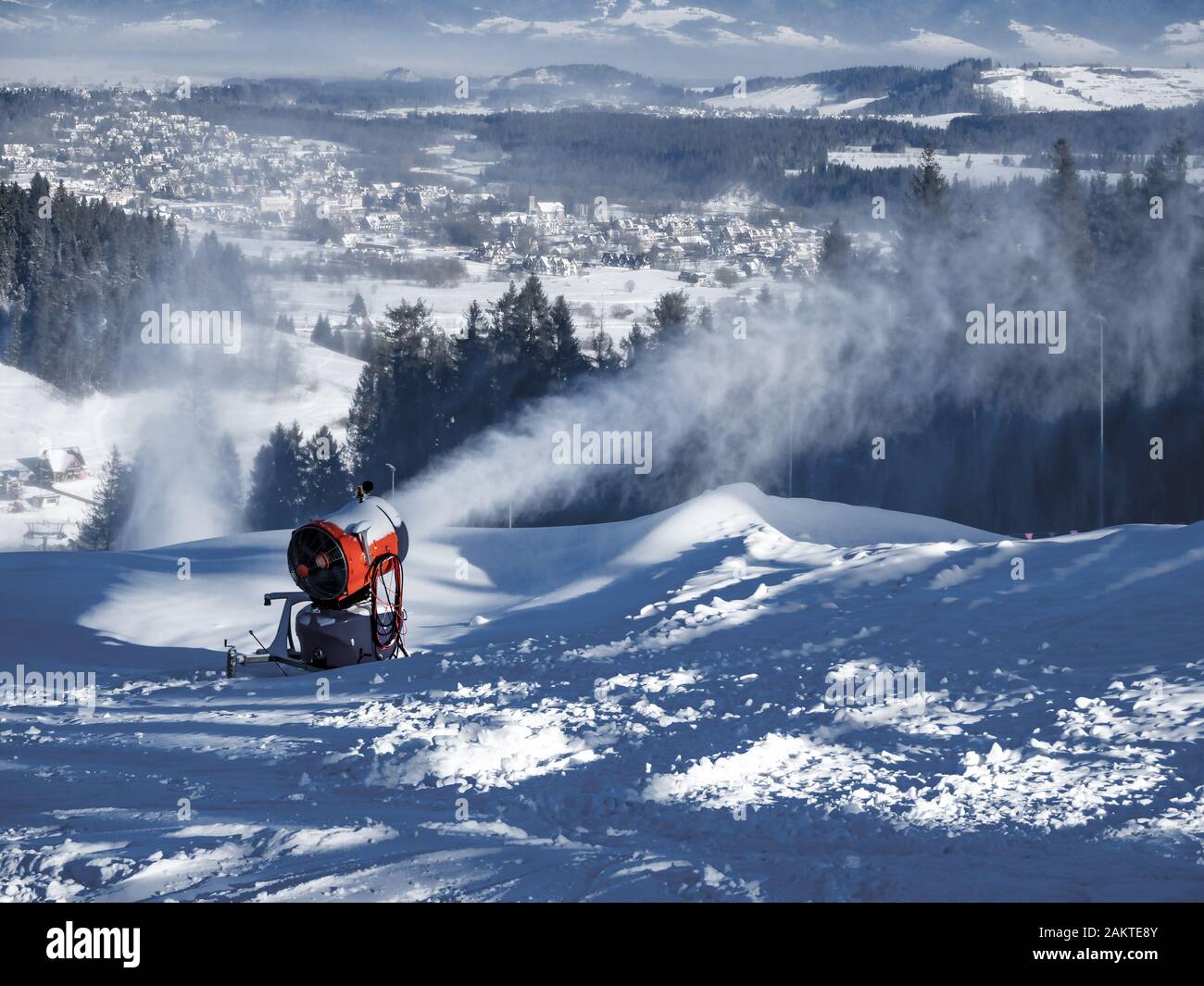Macchina per la produzione di neve, chiamata anche cannone da neve o pistola da neve in azione. Bialka Tatrzanska stazione sciistica in Polonia sullo sfondo Foto Stock