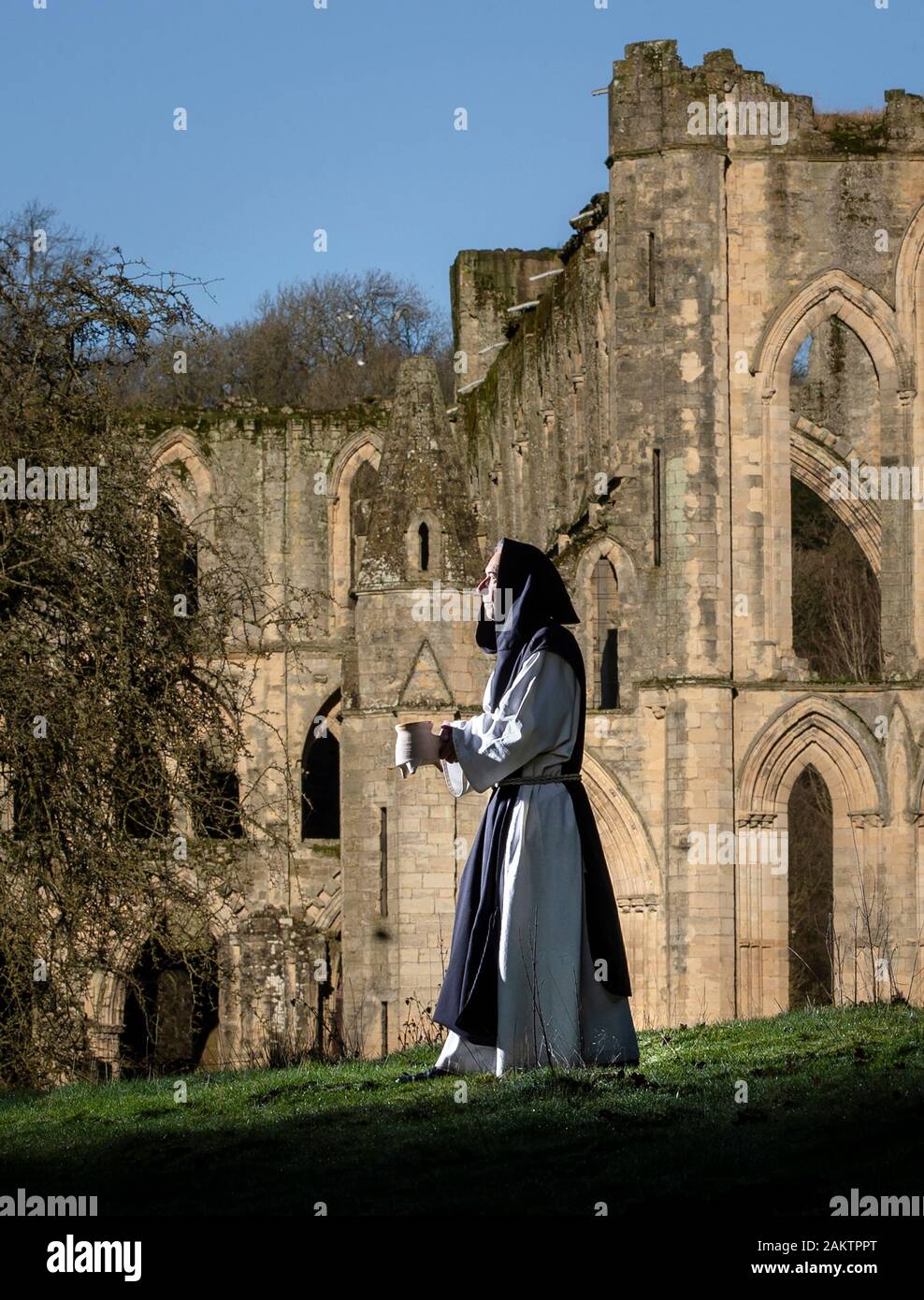 Ri-enactor Tony Powell nel carattere come monaco di Fratel Anthony, tenendo un tradizionale contenente pipkin minestra, uno stufato medievale, al Patrimonio inglese di Rievaulx Abbey in North York Moors National Park. Foto Stock