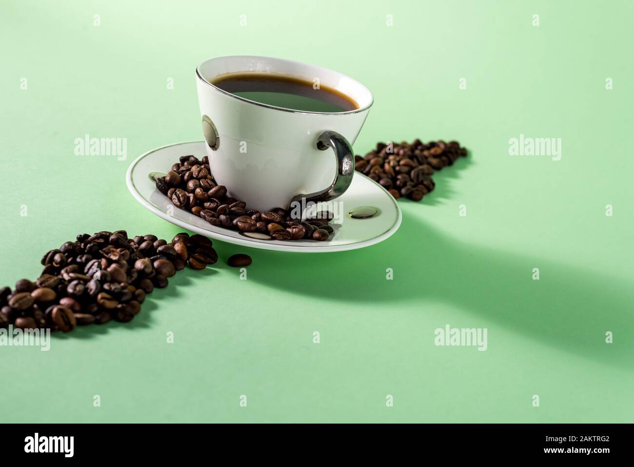 Tazza di caffè e caffè in grani su una luce Sfondo menta Foto Stock