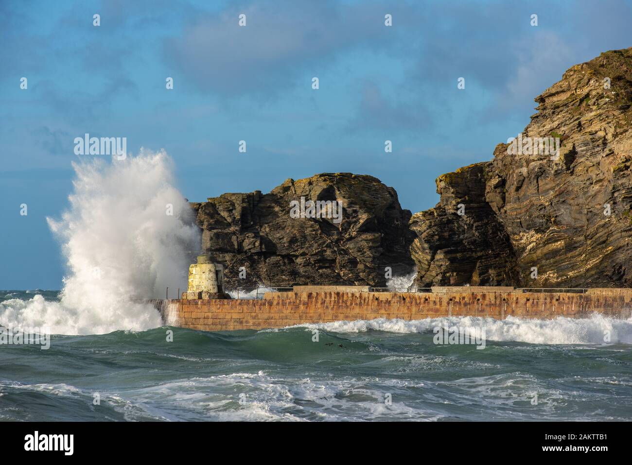 Maltempo a Portreath, Cornwall, Regno Unito con onde che si infrangono sulla capanna di scimmia che fu originariamente costruito come un rifugio per i piloti del porto. Foto Stock