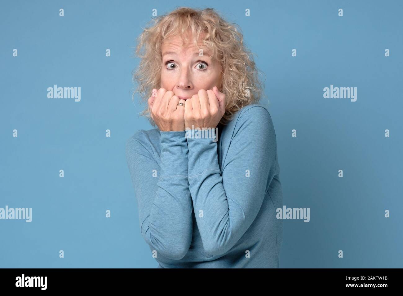 Sistema nervoso donna matura morde le unghie, sentirsi ansioso, afraids dei medici, ha paura di espressione, preoccupazioni che qualcuno conosce il suo segreto. Studio shot Foto Stock