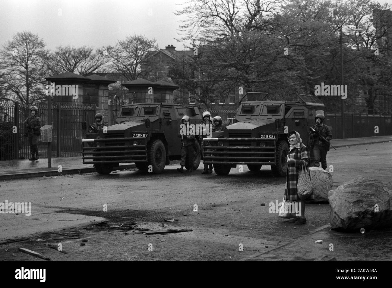 Caricato con shopping un residente locale ignora l'esercito britannico come essi avanzano su un fiammante van a Falls Road, Belfast, dove giovani incappucciati continuato più violente proteste in città. Foto Stock
