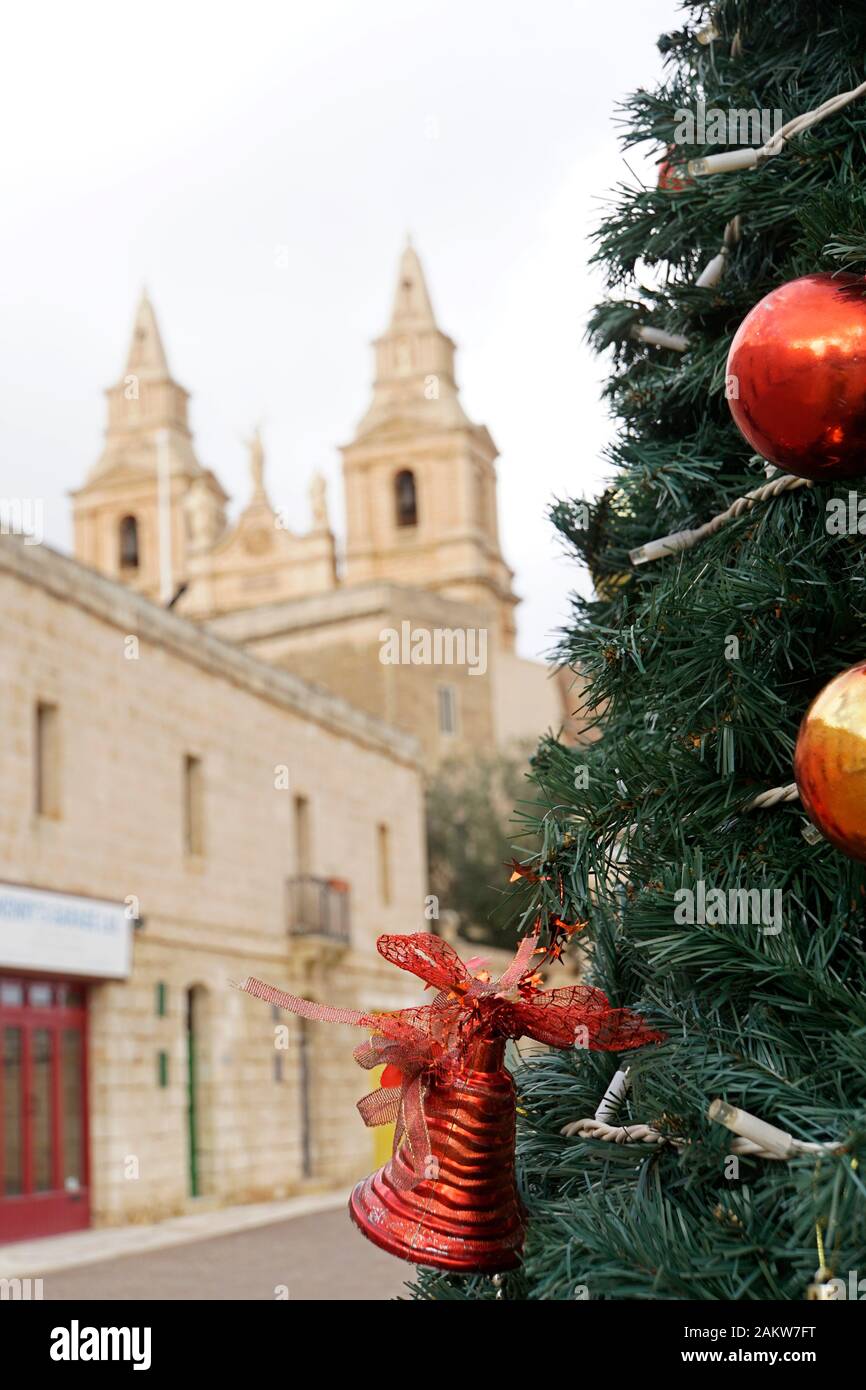 künstlicher Weihnachtsbaum mit Christbaumschmuck in der Altstadt, im Hintergrund die Pfarrkirche Mellieha , Malta Foto Stock