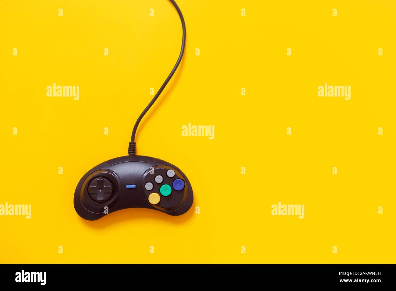 Gamepad cablato nero isolato su giallo. Concetto di giochi per console Foto Stock