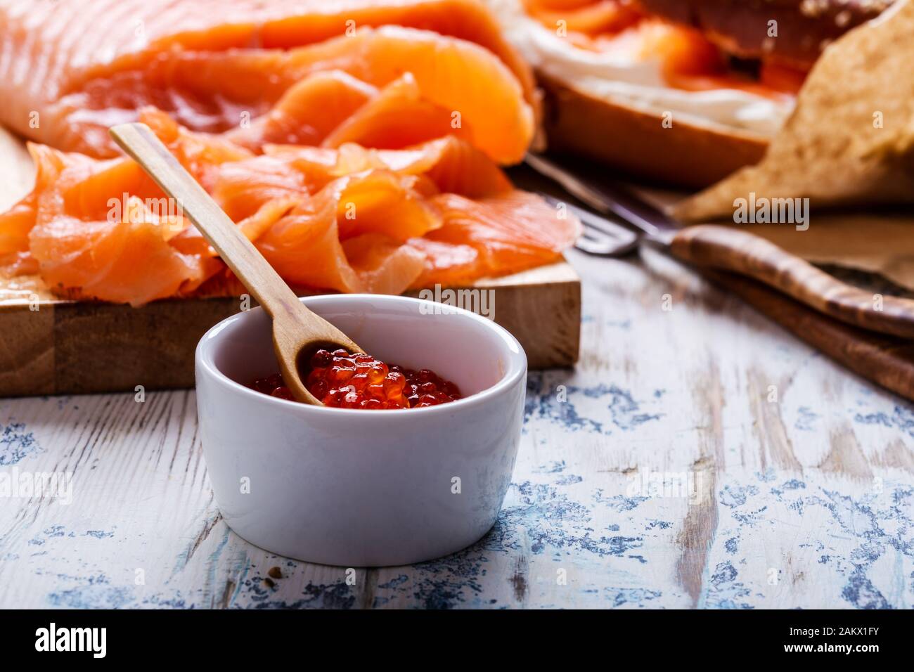 Brunch festivo con salmone curato servito con formaggio cremoso, bagel, pentola di caviale di salmone, avocado, rustico tavolo vicino Foto Stock