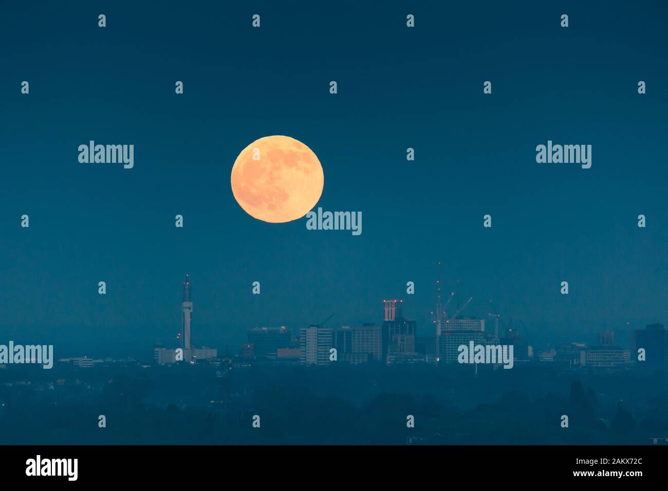 La luna piena o il wolfmoon sta sorgendo sopra la città di Birmingham, Regno Unito Foto Stock