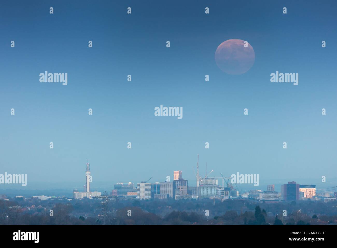 La luna piena o il wolfmoon sta sorgendo sopra la città di Birmingham, Regno Unito Foto Stock