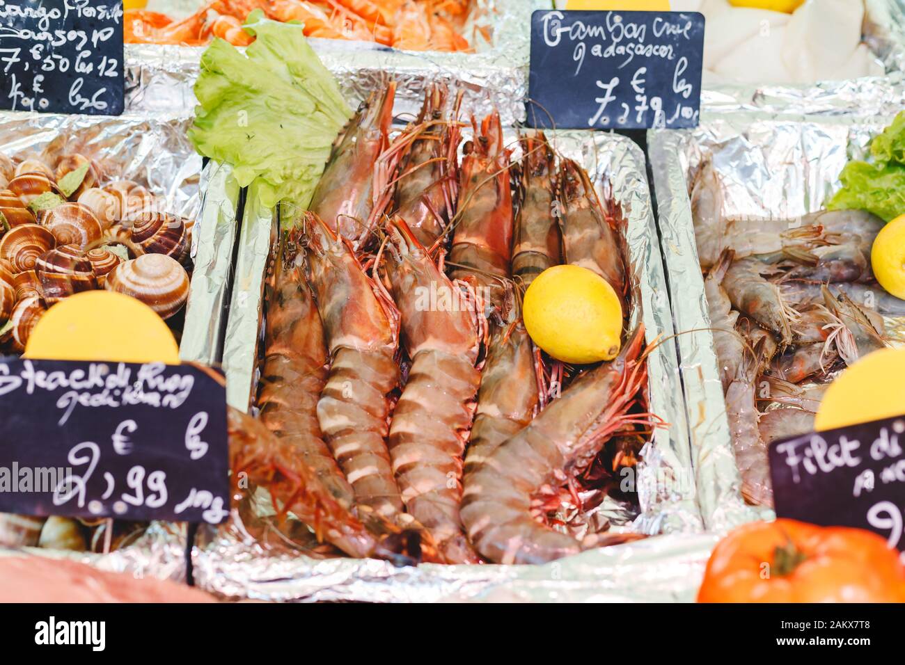 Gamberetti crudi non cotti di grandi dimensioni per la vendita sul mercato degli agricoltori. Mercato alimentare marittimo. Stock foto grandi gamberetti e lumache in scatole di fogli sul mercato a Parigi, Francia Foto Stock