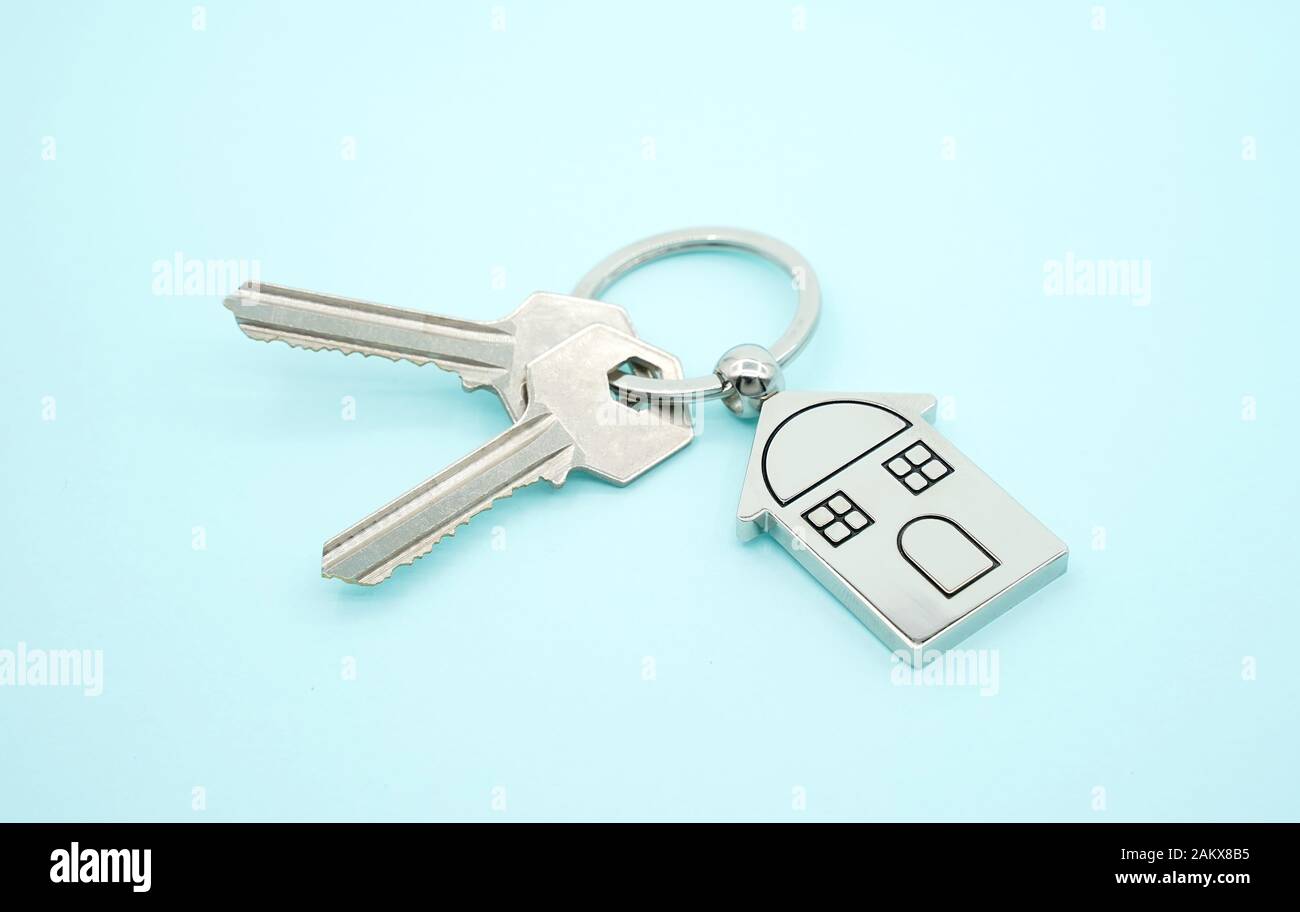 Catena della chiave con il simbolo della casa e le chiavi su sfondo blu,immobiliare di concetto Foto Stock