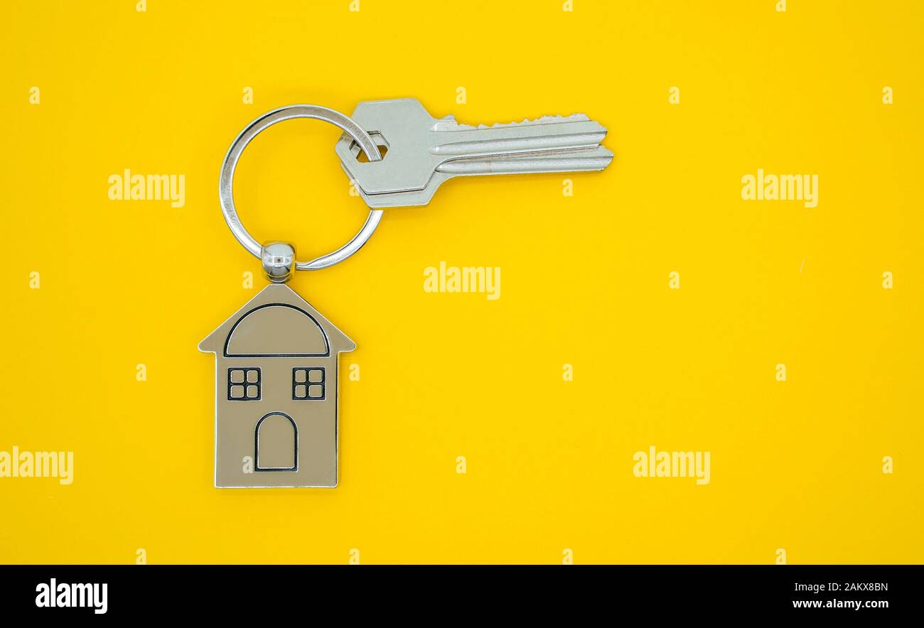 Catena della chiave con il simbolo della casa e le chiavi su sfondo giallo,immobiliare di concetto Foto Stock